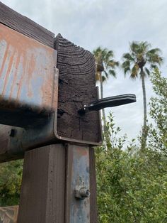 an old rusted metal object with palm trees in the background