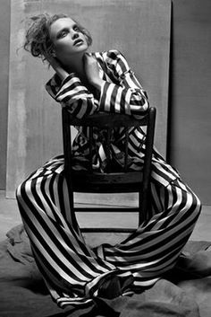 a woman sitting on top of a chair in striped pants and shirt with her arms crossed