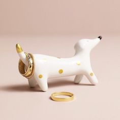 a white dog figurine with gold accents and a ring