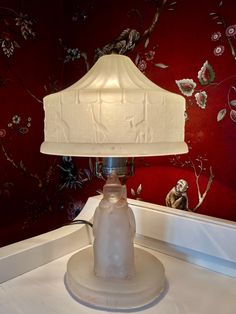 a white lamp sitting on top of a table next to a mirror and red wall