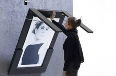 a woman is placing an image on the side of a building with her hands in the frame