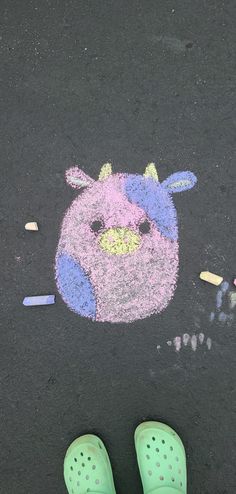 a child's green crocs standing in front of a chalk drawing of a bunny