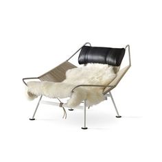 a chair with sheepskin on it and a black leather arm rest in front of a white background