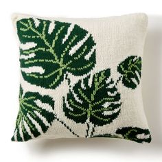 a green and white pillow with leaves on it