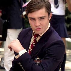 a young man in a suit and tie posing for the camera with his arms crossed