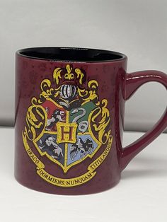 a harry potter mug is shown on a white surface with the hogwarts crest