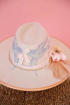 Add a touch of whimsy to your wardrobe with our SONGBIRD RANCHER HAT. This cream hat features charming gold accents and a playful design of blue birds. The beige feather and pink flower combo adds the perfect touch. Stand out from the crowd with this unique and stylish accessory. Cream Hat, Birthday Hats, Bird Birthday, Rancher Hat, Blue Birds, Birthday Hat, Song Bird, Spring 2024, Playful Design