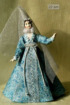 the doll is dressed in blue and has a veil on it's head as she stands with her arms outstretched