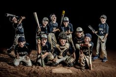 a group of young baseball players posing for a photo in the sand with their bats