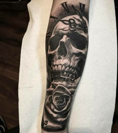 a man with a skull and roses tattoo on his arm is shown in black and white