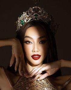 a woman wearing a gold dress with a tiara on her head and red lips