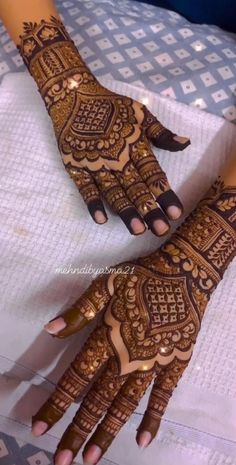 two hands with henna tattoos on them, one is showing off the intricate design