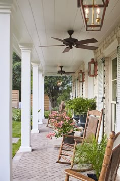 a porch with rocking chairs and plants on it