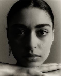 a black and white photo of a woman's face with her hands on her chest