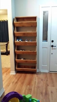 there is a wooden shelf with shoes on it in the room next to a door