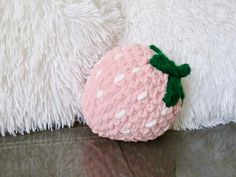 a stuffed strawberry sitting on top of a white pillow