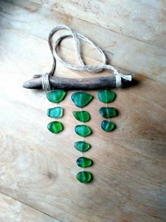 some green glass hearts are hanging from a piece of wood