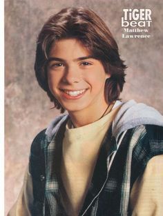 a young man smiling for the camera in front of a magazine cover with an image of him