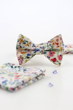 We have sewn an elegant patterned bow tie for you from an amazingly soft and exclusive linen fabric from the manufacturer Liberty London. The fabrics of this manufacturer are known worldwide, with more than a century of tradition. Beautiful floral print on a white background, soft to the touch material, handmade bow tie details, to fine-tune your unique style. The bowtie is firmly reinforced, tied and holds its shape. The accessory is ready for everyday wear, not only for special occasions and weddings. The bow tie is packed for you in an exclusive gift box.  The motif may vary slightly on each bow tie. Bow tie - A unique yet simple element that should form the basis of a man's wardrobe. Our bow ties are a suitable gift for your loved ones if you want to surprise them with a stylish and un Floral Bowtie Groomsmen, Elegant Bow For Gift In Spring, Spring Dapper Adjustable Bow Tie, Dapper Adjustable Bow Tie For Spring, White Spring Party Bow Tie, Spring Wedding Bow, White Bow With Tie Back For Spring, Elegant Bow Tie For Spring Gifts, Satin Bow Tie As Summer Gift