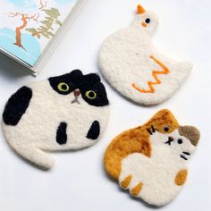 three cat and bird magnets sitting on top of a table next to a book