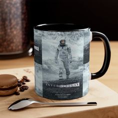 a coffee mug sitting on top of a wooden table next to a spoon and cup