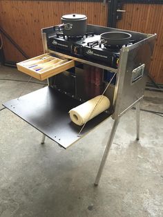 an outdoor stove with two pots on it and a roll of paper under the burner