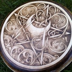 a wooden plate with an intricate design on the outside and inside, sitting in some grass