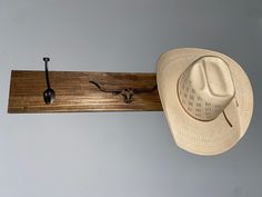 a cowboy hat hanging on a wall next to a hook with a longhorn logo