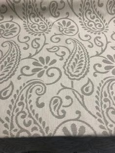 an upholstered bed with a white and grey paisley pattern