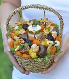 a person holding a wicker basket filled with assorted candies and nuts in it