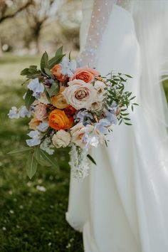 a bridal holding a bouquet of flowers in the grass