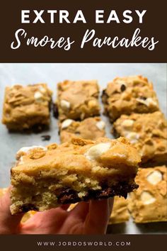 a hand holding up a cookie bar with the words extra easy s'mores pancakes