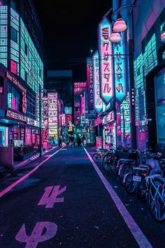 a city street at night with neon signs on buildings and bicycles parked along the side