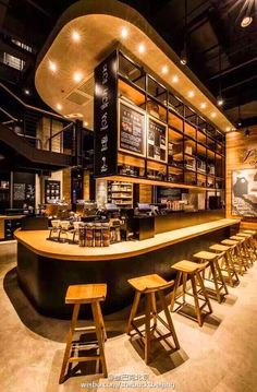 the interior of a restaurant with stools and tables in front of an open bar