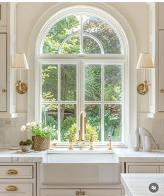 an arched window in a white kitchen with gold handles and knobs on the side