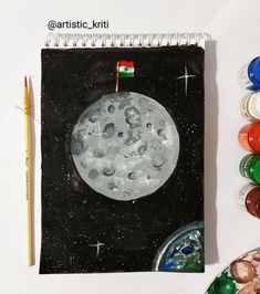 a drawing of the moon with paint and crayons next to it