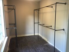 an empty room with two metal racks in the corner and a window on the far wall