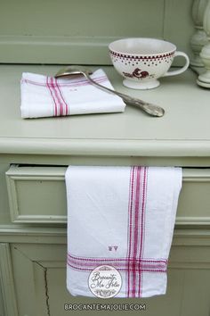 a white and red towel sitting on top of a counter next to a bowl with a spoon