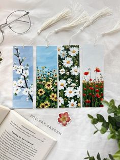 four bookmarks with flowers on them next to an open book and eyeglasses