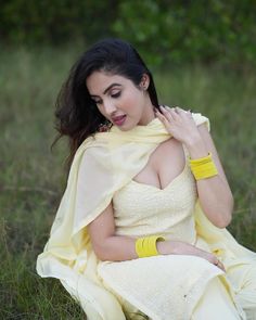 a woman sitting on the ground wearing a yellow dress and holding her hands to her chest