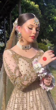 a woman in a wedding dress with flowers on her finger and jewelry around her neck