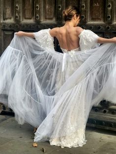 a woman in a white dress is standing on the street with her back to the camera