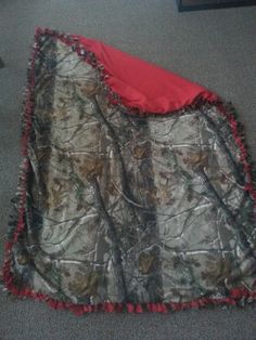 a blanket that is laying on the floor with red trim around it and some other items