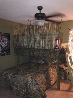 a bedroom with camouflage bedding and ladders to the ceiling in front of it