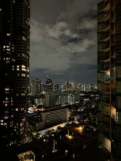 the city skyline is lit up at night with clouds in the sky and lights on buildings