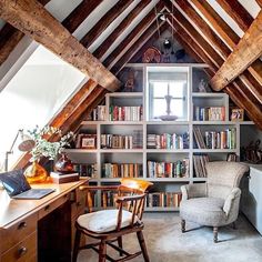 an attic with bookshelves, desk and chair in the corner that has a laptop on it