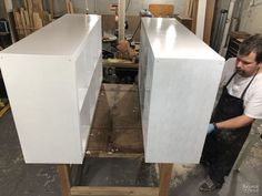 a man working on some white cabinets in a shop