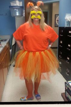 a woman in an orange shirt and yellow tutu skirt with goggles on her head