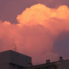 the sky is pink and purple as clouds loom in front of an apartment building