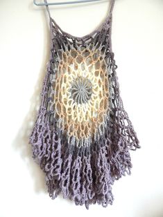 a crocheted top hanging on a clothes hanger with a circular design in the center